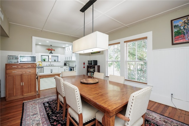 dining room with wooden walls, sink, and hardwood / wood-style flooring