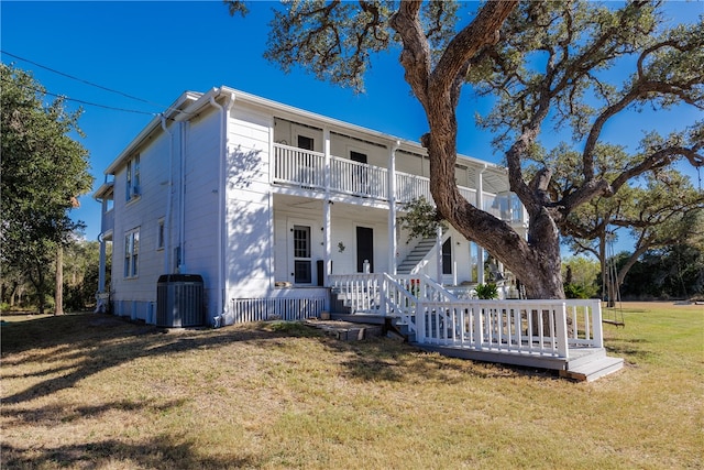 view of front of property featuring central AC, a front yard, and a balcony