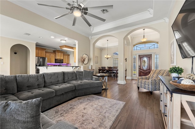 living room with dark hardwood / wood-style floors, ornamental molding, and ceiling fan with notable chandelier