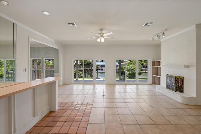 unfurnished living room featuring crown molding, a ceiling fan, a brick fireplace, light tile patterned floors, and track lighting