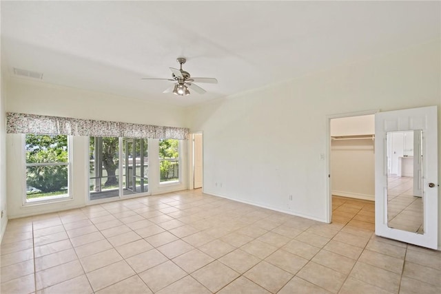 spare room featuring light tile patterned flooring, a ceiling fan, and baseboards