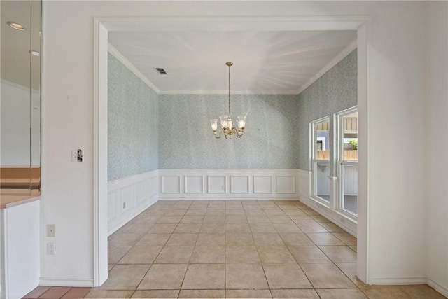 unfurnished dining area with ornamental molding, a chandelier, wallpapered walls, a decorative wall, and wainscoting