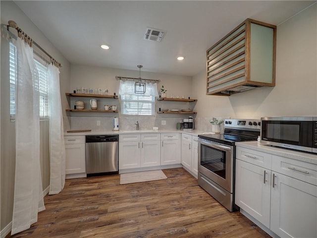 kitchen with pendant lighting, dark wood-type flooring, white cabinetry, backsplash, and stainless steel appliances