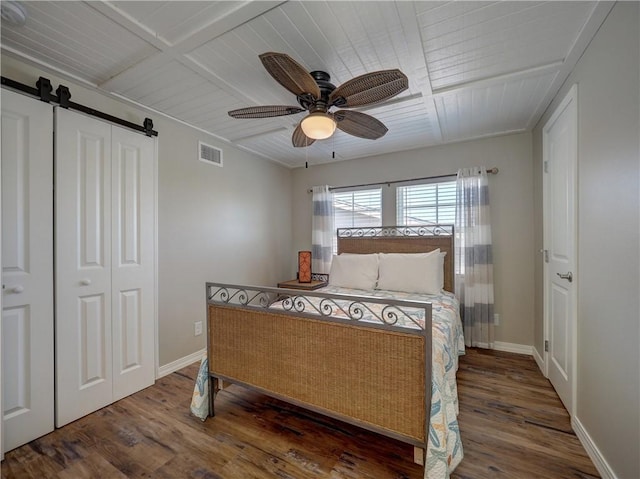 bedroom with a closet, wood-type flooring, a barn door, and ceiling fan