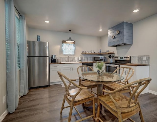 kitchen featuring dark wood-type flooring, sink, hanging light fixtures, appliances with stainless steel finishes, and white cabinets