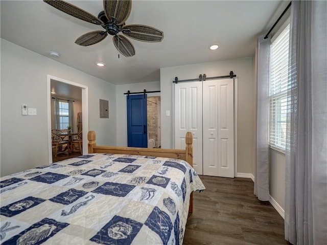 bedroom with dark hardwood / wood-style flooring, electric panel, a barn door, and ceiling fan