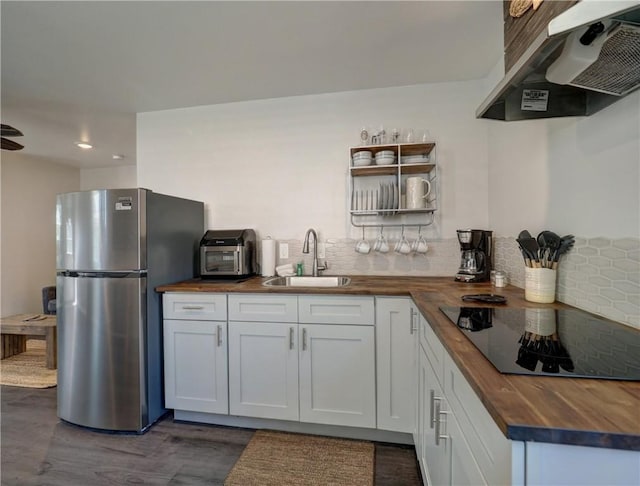 kitchen with extractor fan, butcher block countertops, white cabinetry, sink, and stainless steel fridge