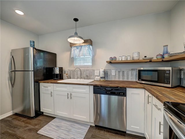 kitchen with pendant lighting, stainless steel appliances, sink, and butcher block countertops