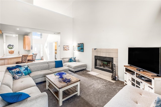 carpeted living room featuring a fireplace and a high ceiling