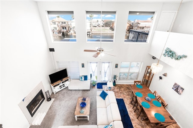 living room with a towering ceiling, plenty of natural light, and ceiling fan