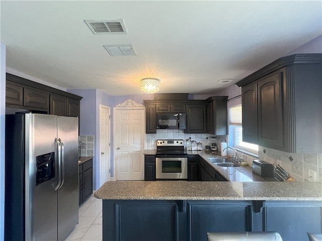 6317 Sir Jack St, Corpus Christi, TX 78414 - kitchen with stainless steel appliances, a peninsula, tasteful backsplash, light marble finish flooring, and dark brown cabinets