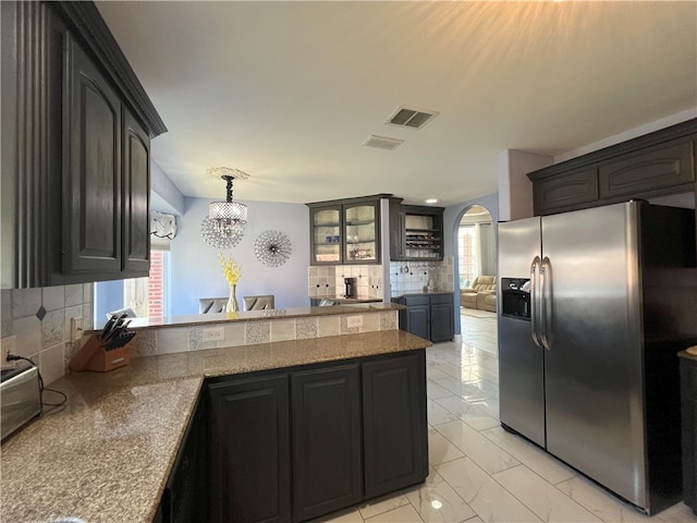 6317 Sir Jack St, Corpus Christi, TX 78414 - kitchen with stainless steel fridge with ice dispenser, a peninsula, backsplash, light marble finish flooring, and a chandelier