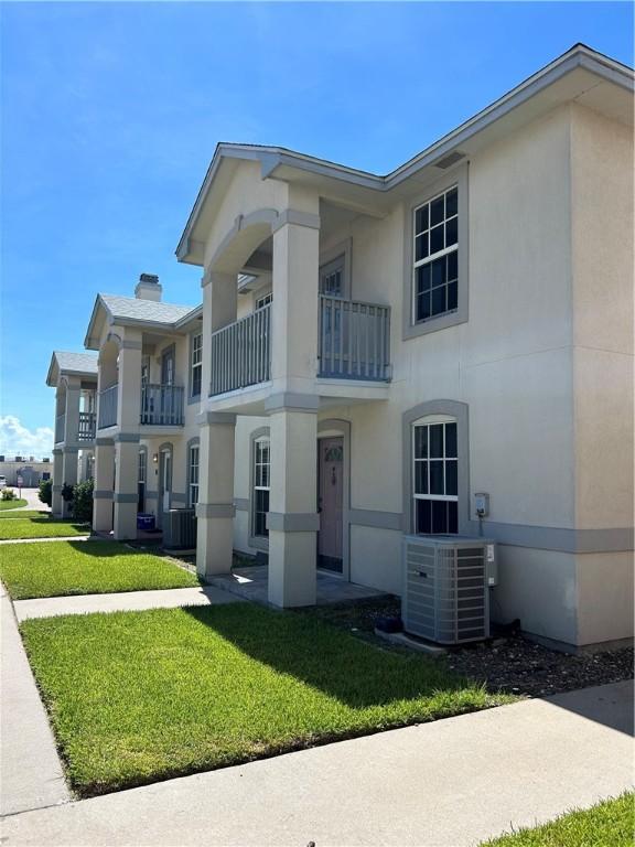 view of front of home featuring a front lawn, cooling unit, and stucco siding