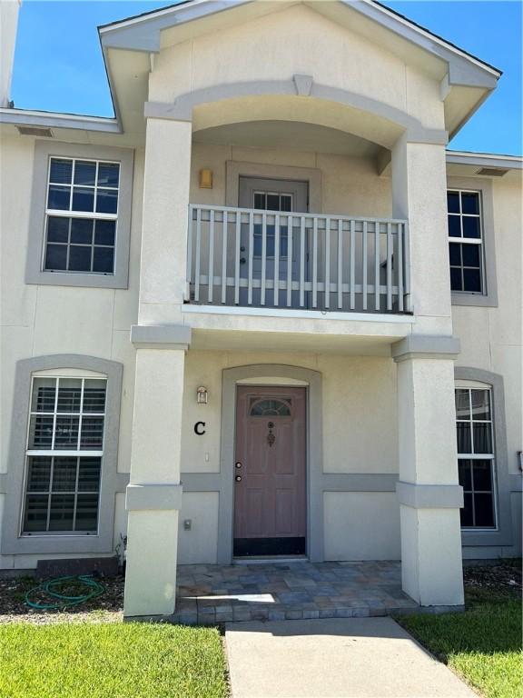 view of exterior entry featuring a balcony and stucco siding