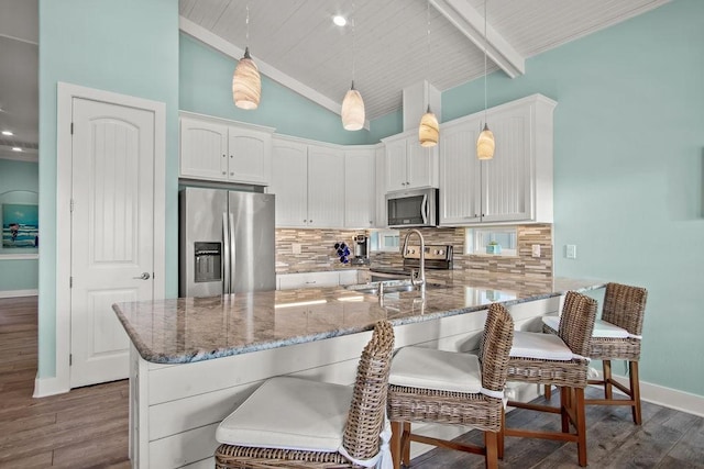 kitchen featuring pendant lighting, dark wood-type flooring, tasteful backsplash, and appliances with stainless steel finishes