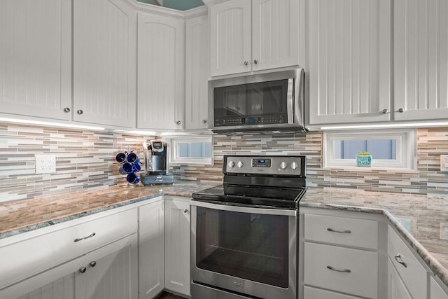 kitchen with light stone counters, decorative backsplash, white cabinets, and appliances with stainless steel finishes