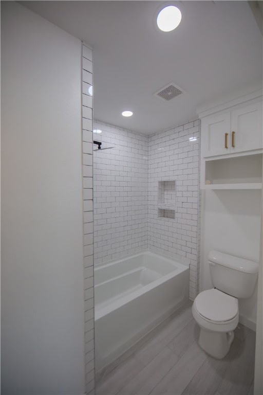 bathroom with toilet and tiled shower / bath