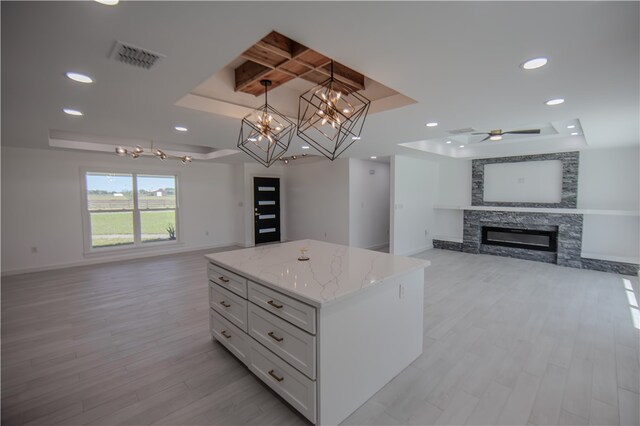 kitchen with white cabinets, decorative light fixtures, a raised ceiling, and a kitchen island