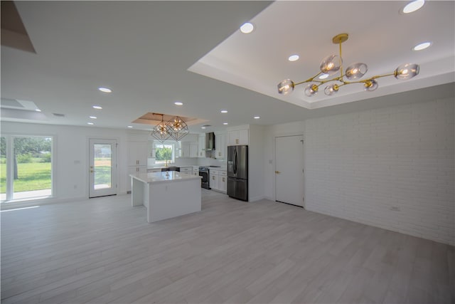 kitchen with a kitchen island, appliances with stainless steel finishes, decorative light fixtures, white cabinets, and a tray ceiling