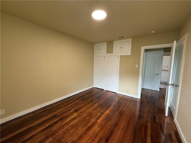 unfurnished bedroom with a closet and dark wood-type flooring