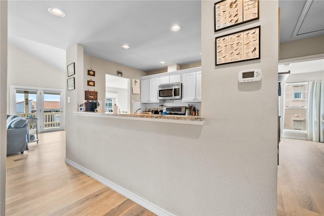 kitchen with white cabinets, light hardwood / wood-style floors, and vaulted ceiling