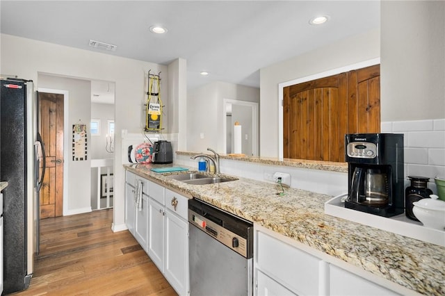 kitchen featuring tasteful backsplash, stainless steel appliances, sink, light hardwood / wood-style flooring, and white cabinetry