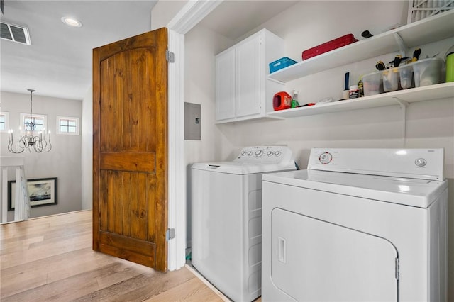 laundry room featuring cabinets, separate washer and dryer, electric panel, a chandelier, and light wood-type flooring