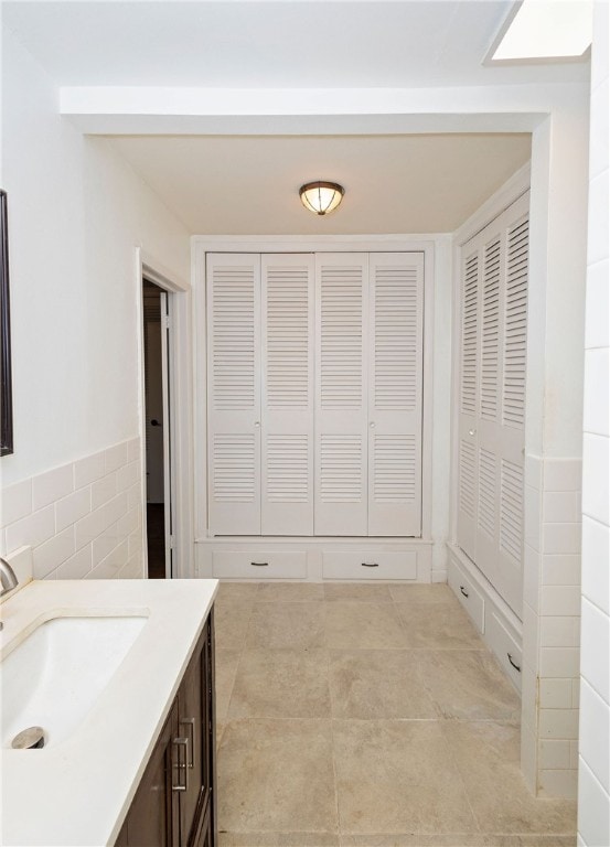 bathroom with tile walls, tile patterned flooring, and vanity