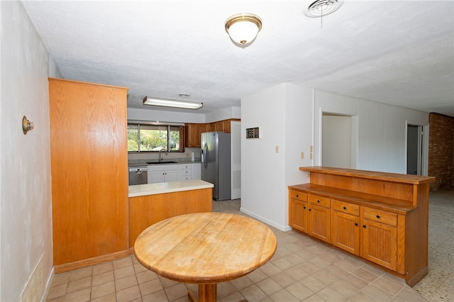 kitchen with a textured ceiling, kitchen peninsula, stainless steel appliances, and sink