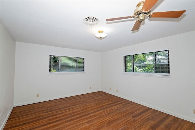 spare room featuring dark wood-type flooring, ceiling fan, and a healthy amount of sunlight