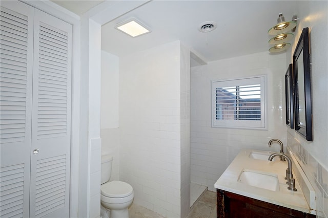 bathroom featuring toilet, vanity, and tile walls