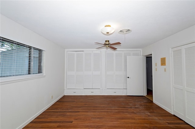 unfurnished bedroom with multiple closets, dark wood-type flooring, and ceiling fan