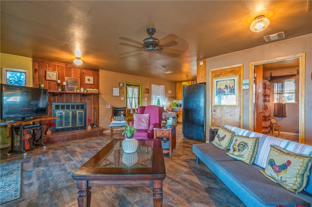 living room featuring ceiling fan and a tile fireplace