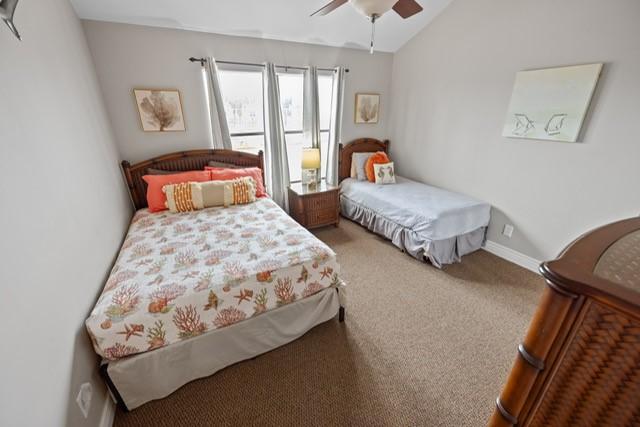 carpeted bedroom with ceiling fan and vaulted ceiling