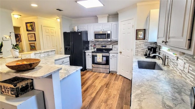 1017 Hickory Ave, Rockport, TX 78382 - kitchen featuring stainless steel appliances, a sink, crown molding, decorative backsplash, and a kitchen bar