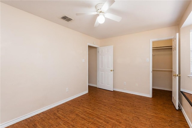 unfurnished bedroom with a spacious closet, visible vents, baseboards, and wood finished floors