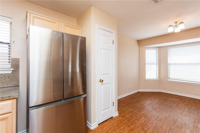 kitchen with light stone counters, light wood-type flooring, freestanding refrigerator, and baseboards