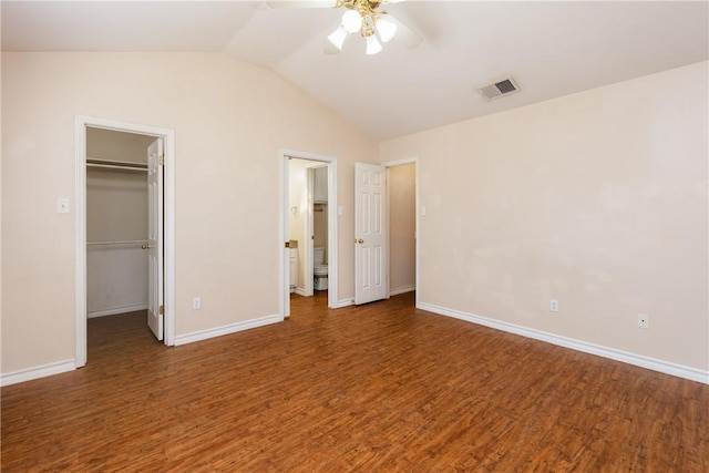 unfurnished bedroom with visible vents, wood finished floors, a walk in closet, and vaulted ceiling