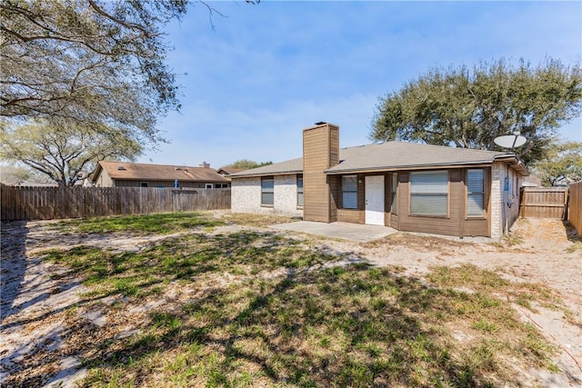 rear view of house with a patio area, a chimney, and a fenced backyard