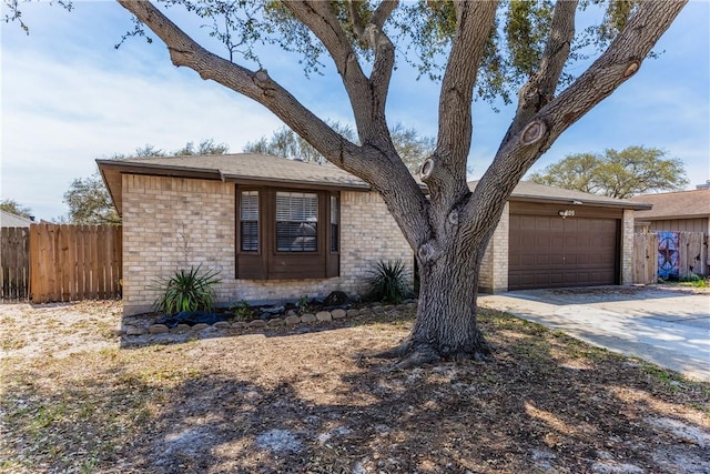 view of front of property with a garage, brick siding, driveway, and fence