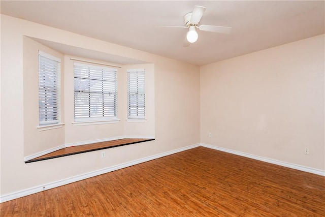 empty room featuring a ceiling fan, baseboards, and wood finished floors