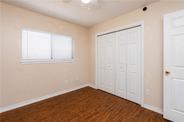 unfurnished bedroom with a closet, baseboards, wood finished floors, and a ceiling fan