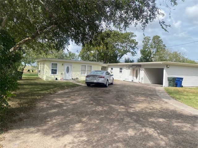 ranch-style home featuring driveway, a front yard, and an attached carport