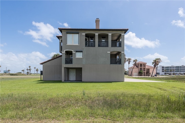 rear view of house featuring a lawn and a balcony