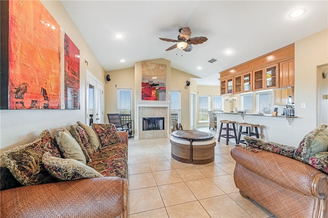 tiled living room featuring ceiling fan, a tile fireplace, and vaulted ceiling