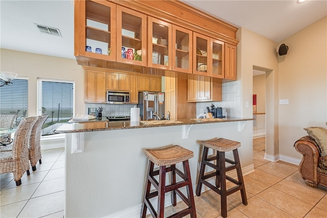 kitchen featuring stone counters, light tile patterned floors, backsplash, and appliances with stainless steel finishes