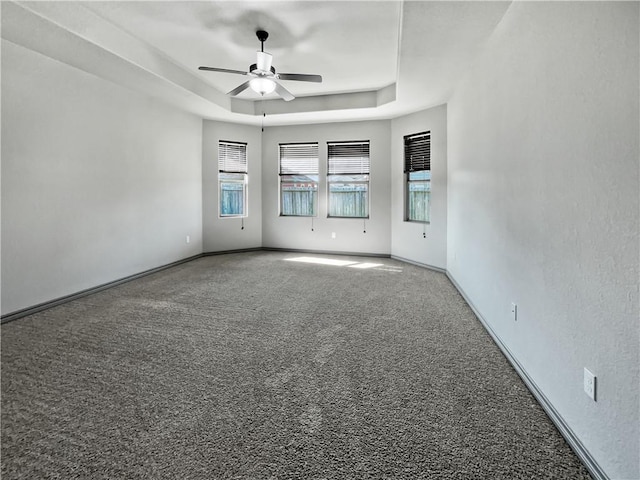 unfurnished room featuring a raised ceiling, ceiling fan, and carpet flooring