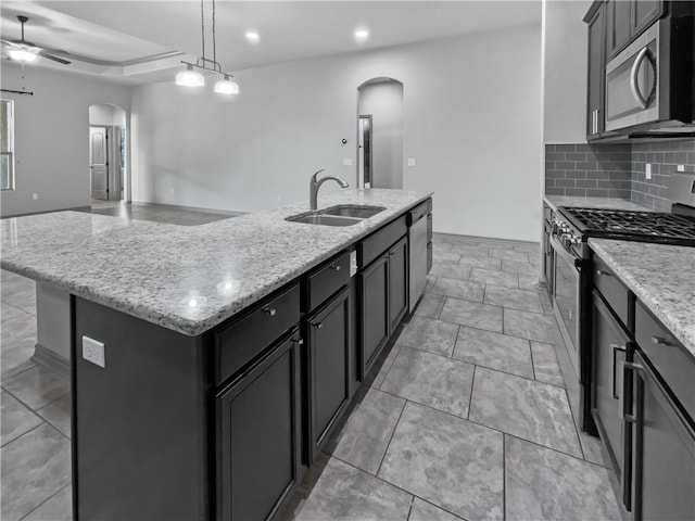 kitchen with a center island with sink, sink, hanging light fixtures, ceiling fan, and stainless steel appliances