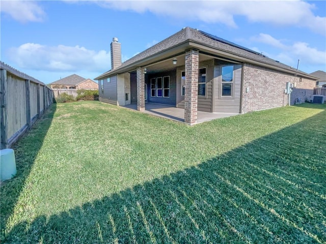 rear view of property with a lawn, cooling unit, and a patio