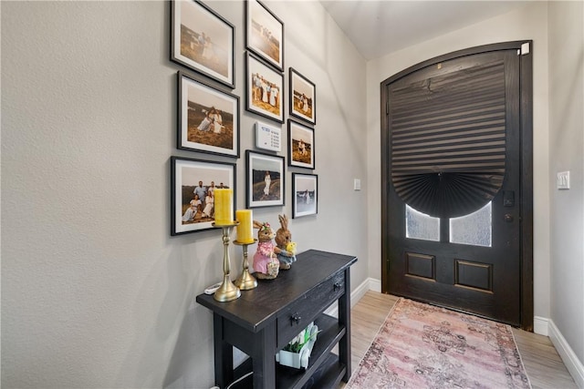foyer entrance featuring baseboards and light wood-style floors